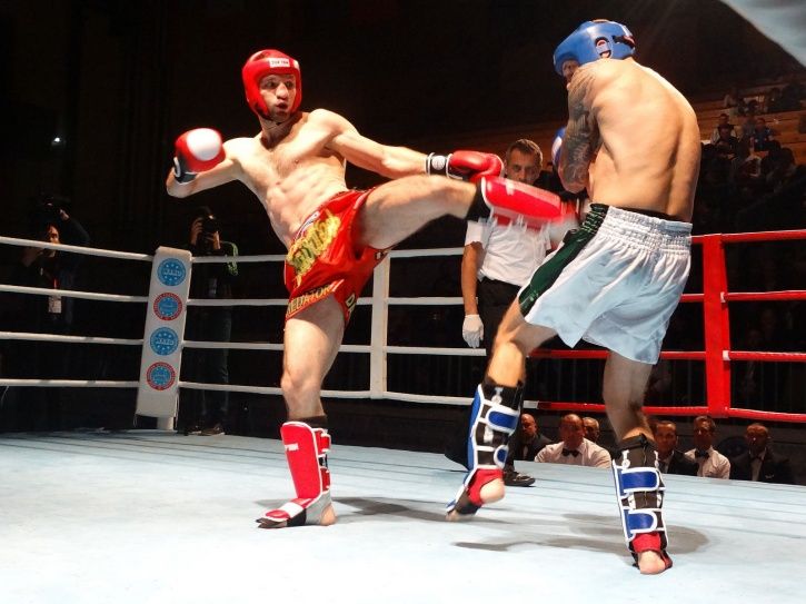 Two kickboxers sparring in a ring with one fighter landing a high kick to the opponent