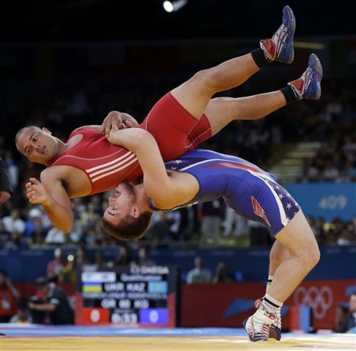Two wrestlers competing at an Olympic-level match with one athlete executing a throw